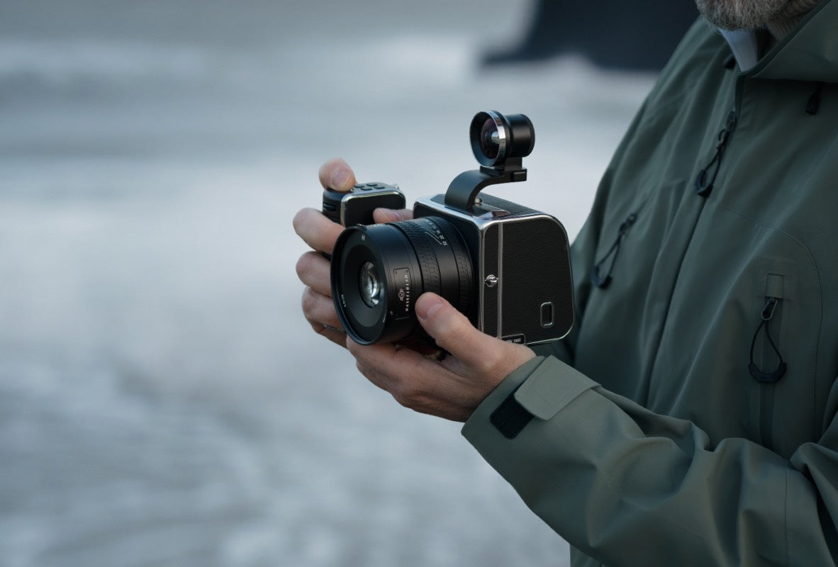 Fotograf hält eine Hasselblad Mittelformatkamera mit Weitwinkelobjektiv im Freien