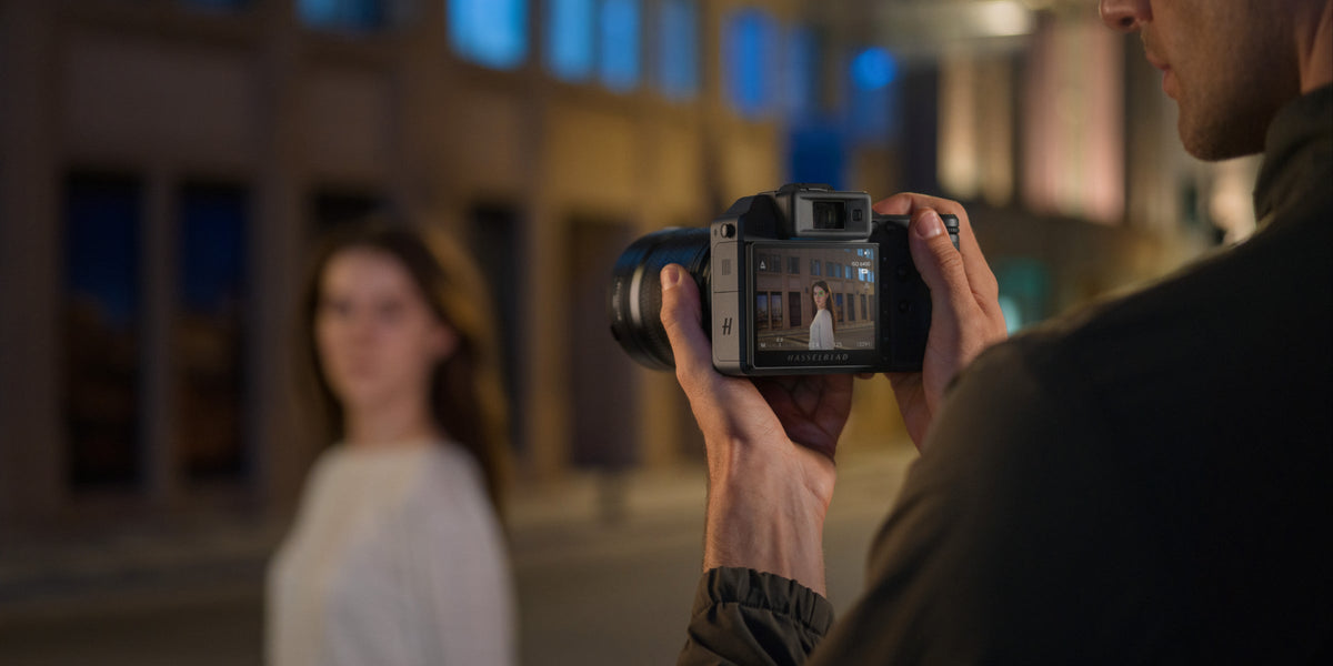 Fotograf porträtiert eine Frau nachts auf der Straße mit einer Hasselblad-Kamera